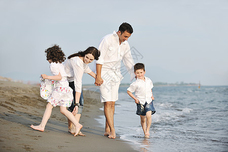 快乐的年轻家庭在海滩上玩得开心海洋喜悦假期跑步乐趣旅行女儿天空童年父母图片