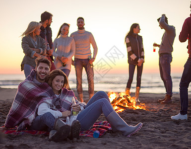 在海滩日落时和朋友共度欢乐的情侣乐趣城市沙滩营火假期友谊衣服幸福朋友们快乐图片