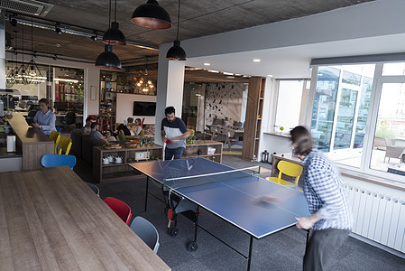 在有创意的办公空间打乒乓网球男性桌子女士女性职场优胜者商务欢呼人士同事图片