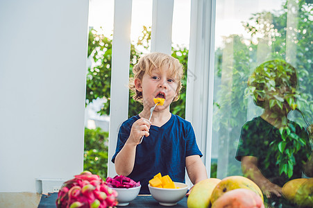小可爱男孩在阳台上吃芒果甜点情调微笑沙拉幸福孩子乐趣异国营养水果图片