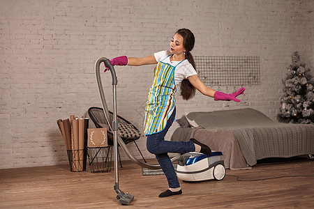快乐的女人打扫家门 与吸尘器清洁者共舞 玩得开心 复制空间唱歌女性地面成人相机公寓吉他家庭音乐生物图片