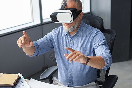成熟商务人士坐在现代办公室时戴着VR头盔 改变你对世界的观感和体验方式 笑声沉思承包商建筑学安全帽愿望衣领男人检查投资经理图片