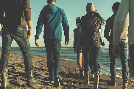 秋天在海滩上奔跑的一群朋友年轻人跑步海岸假期友谊鹅卵石啤酒服装幸福朋友们图片