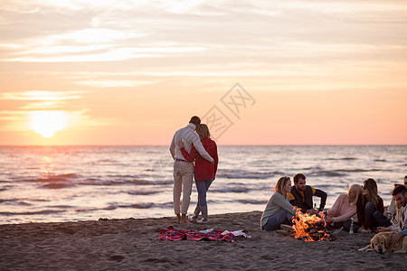 在海滩日落时和朋友共度欢乐的情侣活动城市休闲快乐派对啤酒篝火沙滩营火夫妻图片