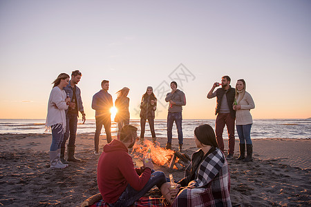 在海滩日落时和朋友共度欢乐的情侣营火幸福女性衣服旅行享受友谊夫妻潮人派对图片