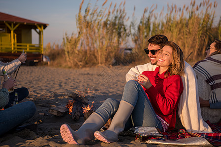在海滩日落时和朋友共度欢乐的情侣沙滩火焰旅行休闲动作夫妻活动场景朋友们衣服图片