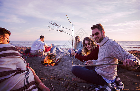 在海滩日落时和朋友共度欢乐的情侣夫妻派对友谊潮人火焰男人城市乐趣沙滩篝火图片