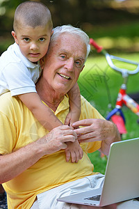 使用笔记本电脑的儿童学习退休金融互联网男生家庭公园保险男人商业背景图片