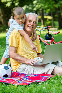 使用笔记本电脑的儿童老年头发祖父商业公园退休喜悦男人冲浪家庭背景图片