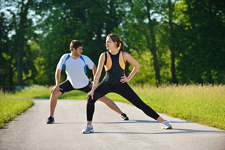 户外跑步两人在慢跑后做伸展运动青少年女孩公园夫妻训练健康乐趣天空男性成人背景