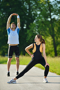 人们在慢跑后做伸展运动健康男性青年跑步锻炼公园女性训练成人天空图片