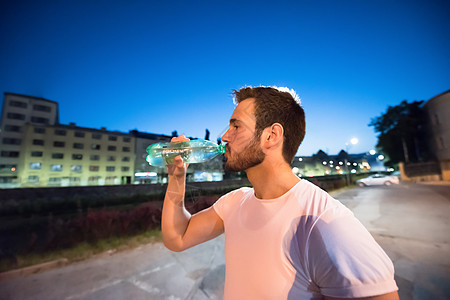 户外跑步男人在自来水处理后饮用饮用水运动员城市瓶子活力补水会议训练运动男性街道背景