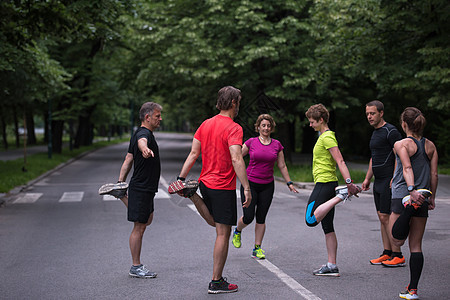 早上训练前暖化和伸展的赛跑队成人团队慢跑者热身公园跑步运动员男性运动装竞赛图片