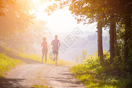 森林跑步年轻夫妇在大自然阳光明媚的日子慢跑活动日落训练女朋友运动装农村男人女士练习森林背景