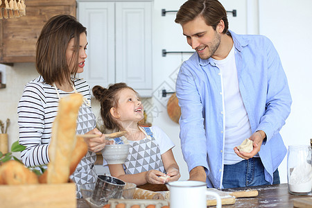 可爱的小女孩和她的父母一起在家厨房做饭时 玩得很开心 还在一起吃饭呢蔬菜童年午餐成人男人父亲食物食谱女儿微笑图片