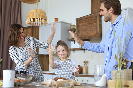 可爱的小女孩和她的父母一起在家厨房做饭时 玩得很开心 还在一起吃饭呢平底锅午餐微笑童年勺子男性父亲食谱蔬菜爸爸图片