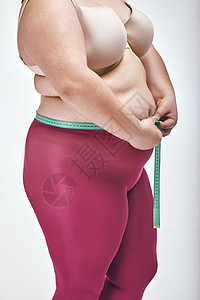 胖胖女人在用白色背景测量她的肚子生活饮食腹部减肥乐趣女性重量管状动机肥胖背景