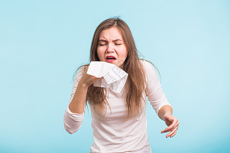 年轻女人的蓝底鼻子有根流鼻涕成人过敏发烧鼻音感染手帕疾病小伙子青少年疼痛图片