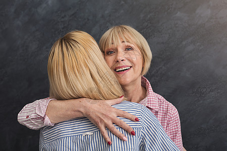 母亲老快乐的成年母亲和女儿拥抱灰色背景女性会议房间亲戚们喜悦中年家庭客人时间幸福背景