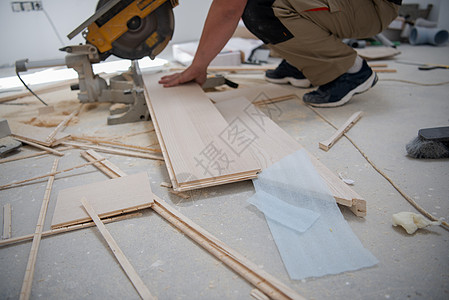 男子用电环锯锯切割压板地板木板男人仪表木地板工人木匠建设者建筑测量工作工具图片
