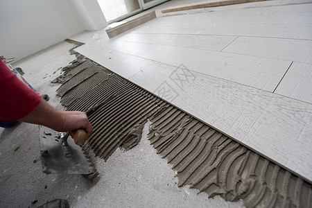在地板上安装陶瓷木效应瓦板的工人装修材料男人工作职场地面木匠木地板陶瓷压板图片