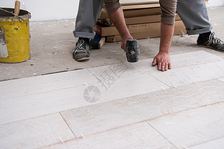 在地板上安装陶瓷木效应瓦板的工人控制板房子建筑学男性陶瓷木板公寓瓦工职场建筑图片