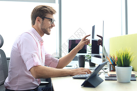 穿着衬衫的有想象力的年轻商务人士在办公室里站着时使用计算机工作图片