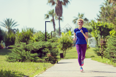 参加马拉松比赛的年轻女青年选手培训棕榈赛跑者公园热带森林阳光耐力女士跑步踪迹图片