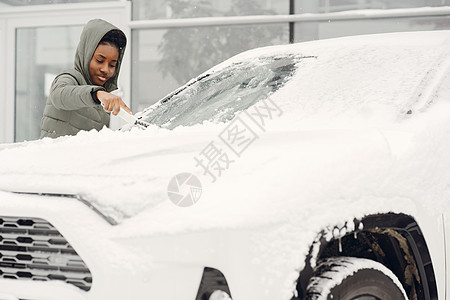 妇女从汽车挡风玻璃上除雪窗户冻结车辆刷子玻璃运输街道司机暴风雪夹克图片