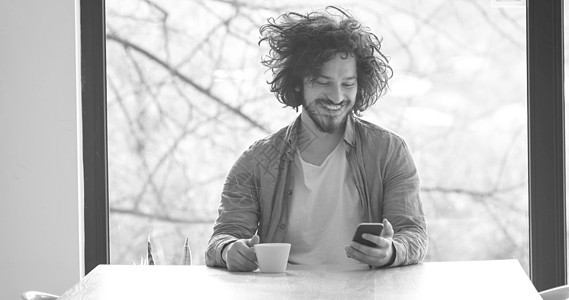 青年男子在家中喝咖啡和手机 并使用手机快乐成人咖啡互联网技术奢华电脑沙发阅读网络图片