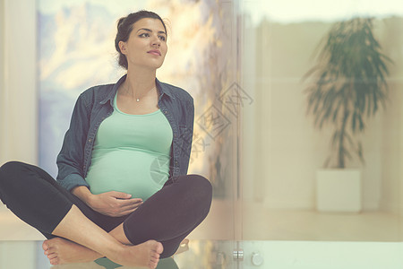 坐在地板上怀孕的孕妇地面母亲婴儿身体女性母性客厅父母享受幸福图片