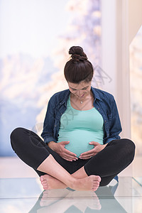 坐在地板上怀孕的孕妇女性母亲客厅腹部父母地面身体母性女士生活图片