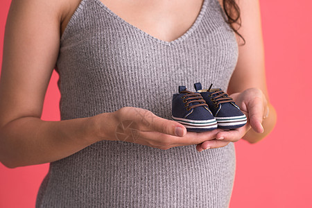穿着小婴儿鞋的怀孕妇女腹部成人母性工作室女性妈妈家庭父母肚子孩子图片
