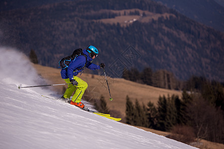 滑雪者在下坡时玩得开心高山天空晴天冻结速度旅行乐趣行动滑雪季节图片