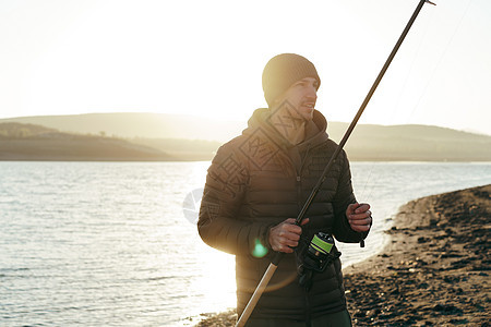 一名带渔棍的年轻男性渔民的肖像衣服运动成人渔夫爱好活动钓鱼闲暇喜悦男人图片