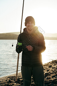 一名带渔棍的年轻男性渔民的肖像男人运动爱好钓鱼渔夫喜悦垂钓者活动闲暇衣服图片