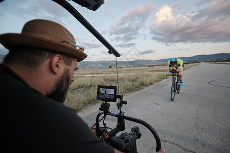 视频摄影师在骑自行车时拍摄Triathlon运动员的动作镜头运动电影铁人制片人摄影相机生产钢铁侠稳定性耐力图片
