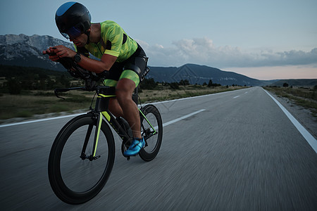 夜间骑自行车的三重运动员轮子速度耐力钢铁侠导航头盔运动行动竞赛健康图片