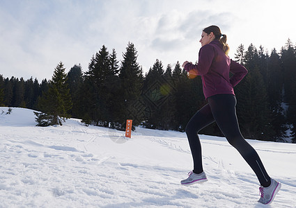 年青女人在森林雪上户外慢跑跑步活动赛跑者娱乐小路踪迹运动装损失天气运动员图片