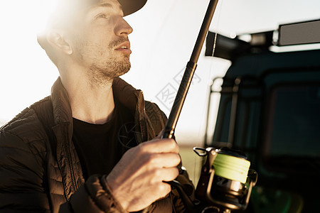 一名带渔棍的年轻男性渔民的肖像活动垂钓者闲暇爱好衣服钓鱼渔夫喜悦成人男人图片