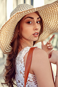 穿着白衣服的时装黑发女人 草帽 街上行走 在商店窗户附近摆姿势玻璃女性女孩帽子珠宝销售配件太阳镜棕榈街道图片