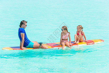 暑假期间在冲浪板上的父亲和孩子海岸女儿乐趣支撑海滨假期冲浪爸爸女孩海浪图片