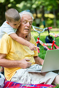 使用笔记本电脑的儿童祖父商业老年男生头发喜悦冲浪保险家庭微笑背景图片