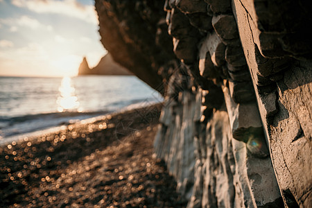 日落时海滩上的壮丽海景 温暖的夕阳照亮了岩石火山悬崖 晴空无云 没有人 平静沉默和与自然统一的概念 选择性焦点图片