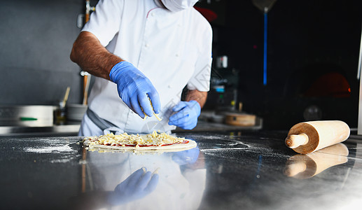 厨师用保护性冠状病毒面罩做披萨潮人食物烹饪餐厅食谱木头火焰烤箱职业商业图片