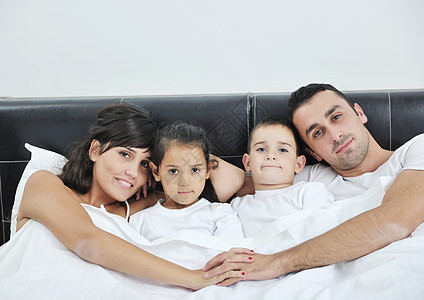 幸福的年轻家庭在他们的卧室中男性母亲儿子男人女士拥抱夫妻女性喜悦妈妈图片