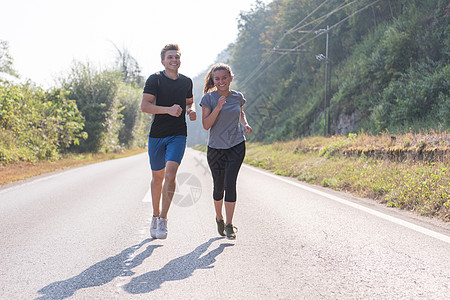 在乡村公路上慢跑的年轻夫妇森林男性女孩训练活动跑步运动员阳光运动装男人图片