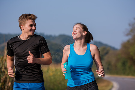 在乡村公路上慢跑的年轻夫妇运动员运动成功森林农村赛跑者活力慢跑者跑步女性图片