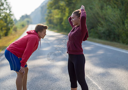年轻夫妇在乡村公路上升温和伸展夫妻活动运动员跑步国家热身赛跑者女孩运动装森林图片
