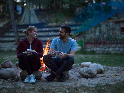 晚上在营火周围坐着一对夫妇家庭男朋友约会闲暇杯子篝火成人乐趣男性友谊图片